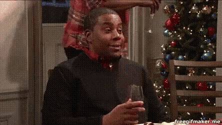 a man is holding a wine glass in front of a christmas tree