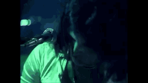 a man is singing into a microphone while playing a keyboard in a dark room .
