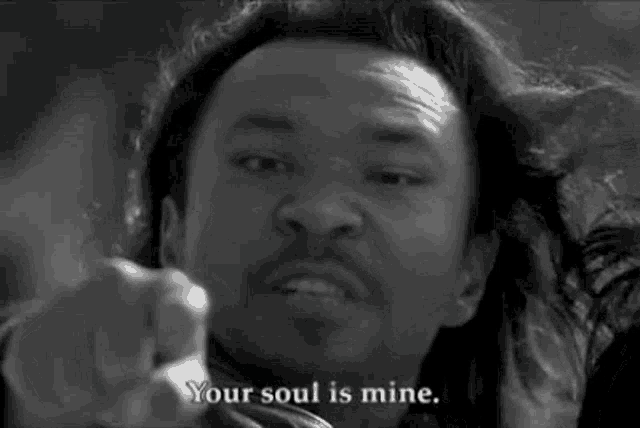a black and white photo of a man pointing at the camera with the words `` your soul is mine '' .