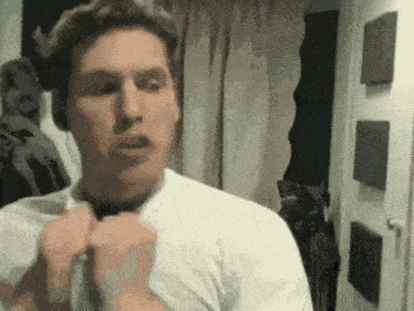 a man in a white shirt is adjusting his shirt