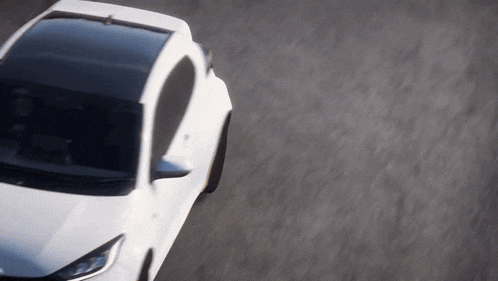 a white car is driving down a road with a black roof