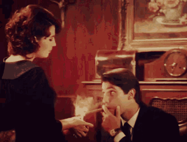 a man is smoking a cigarette while a woman holds a lighter