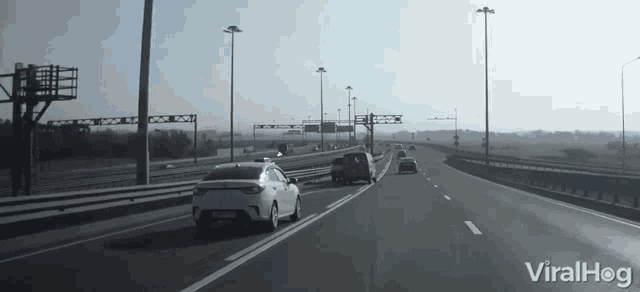 a white car is driving down a highway with a viralhog logo in the corner