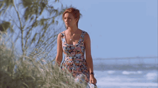a woman in a floral dress is standing in the grass