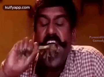 a man with a mustache is eating a piece of food with his mouth open .