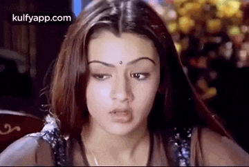 a woman with long hair and a bindi on her forehead is making a funny face .