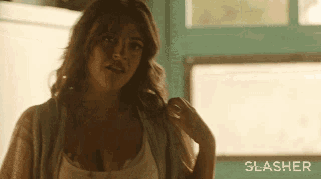 a woman is standing in front of a window with the word slasher on the bottom right