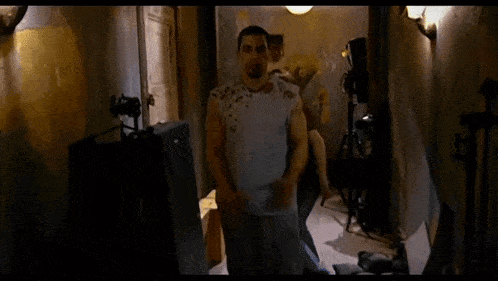 a man in a white shirt is standing in a dark room