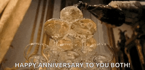 a bottle of champagne is poured into a stack of champagne glasses with the words happy anniversary to you both
