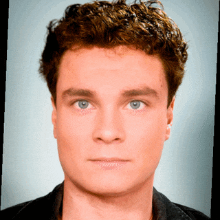 a young man with curly hair looks at the camera
