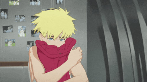 a boy with yellow hair is covering his face with a red sweater