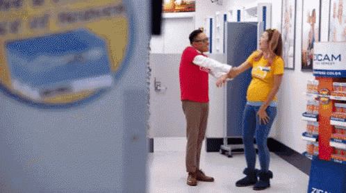 a man in a red shirt is standing next to a pregnant woman in a yellow shirt