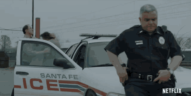 a santa fe police officer is standing in front of a car