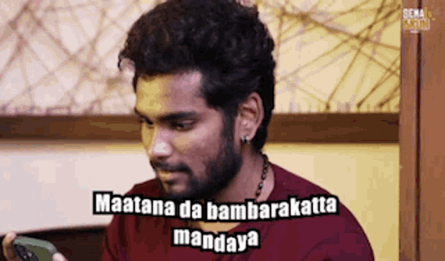 a man with a beard is holding a cell phone and says " maatana da bambarakka mandaya "