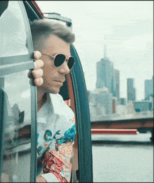 a man wearing sunglasses looks out of a window