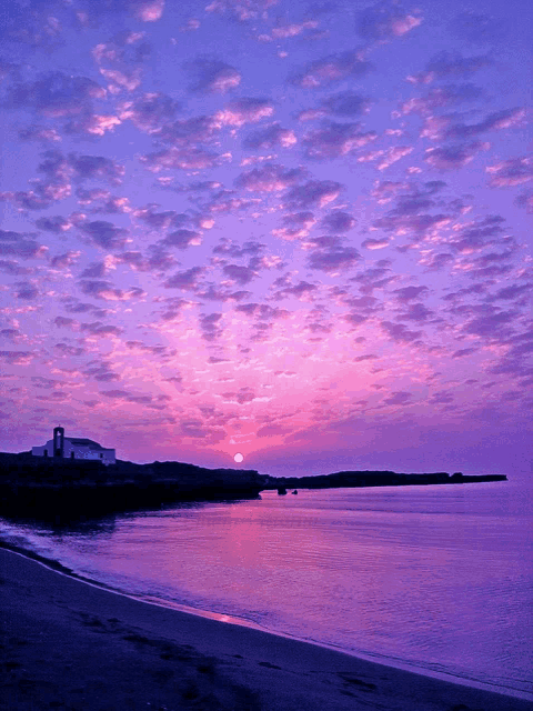 a sunset with purple clouds over the ocean