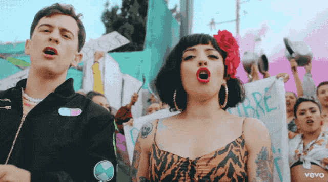 a man and a woman singing in front of a crowd with a sign that says ' libre '