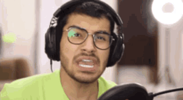 a man wearing headphones and glasses making a funny face .