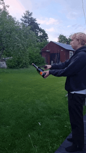 a man in a black hoodie is holding a bottle of wine in his hand