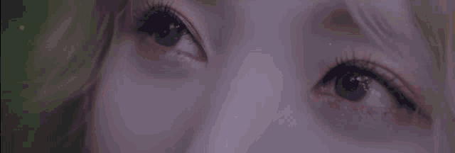 a close up of a woman 's eyes with long eyelashes looking up at the sky .