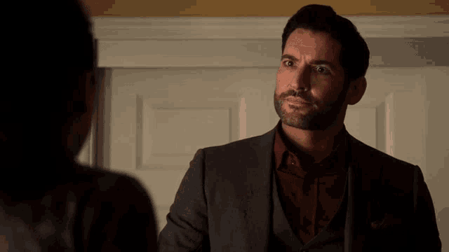 a man in a suit is talking to a woman in a dark room