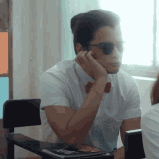 a man wearing sunglasses is sitting at a desk