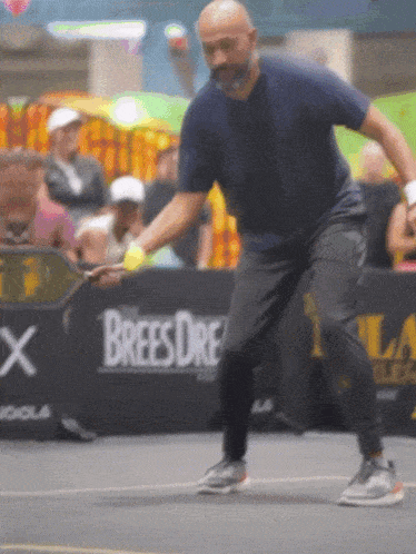 a man playing tennis in front of a brees dre advertisement