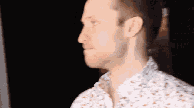 a man with a beard is wearing a white shirt with a floral pattern .