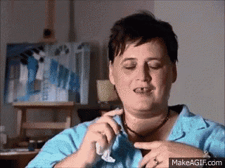 a woman in a blue shirt is holding a napkin to her face .