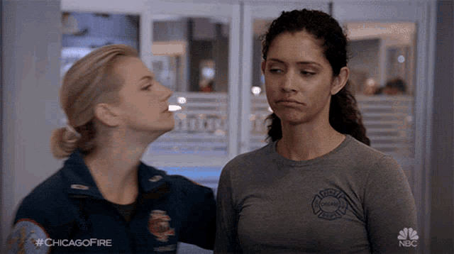 two women are standing next to each other and one has a chicago fire badge on her shirt