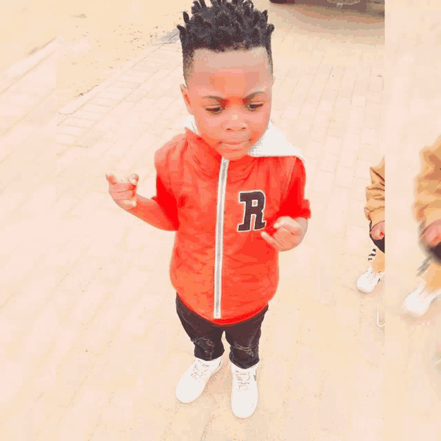 a young boy wears a red jacket with the letter r on it