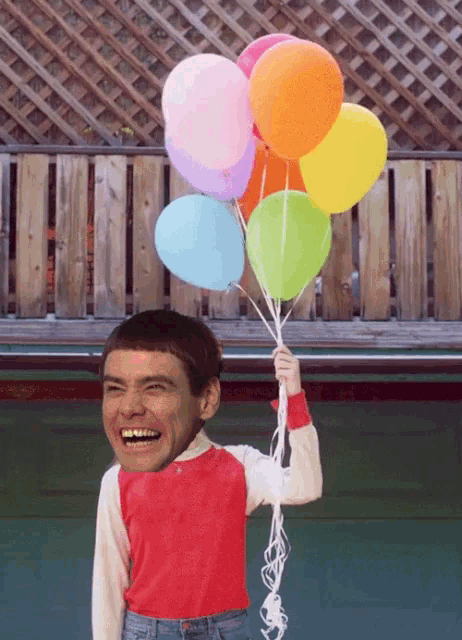 a boy in a red shirt is holding a bunch of balloons in his hand