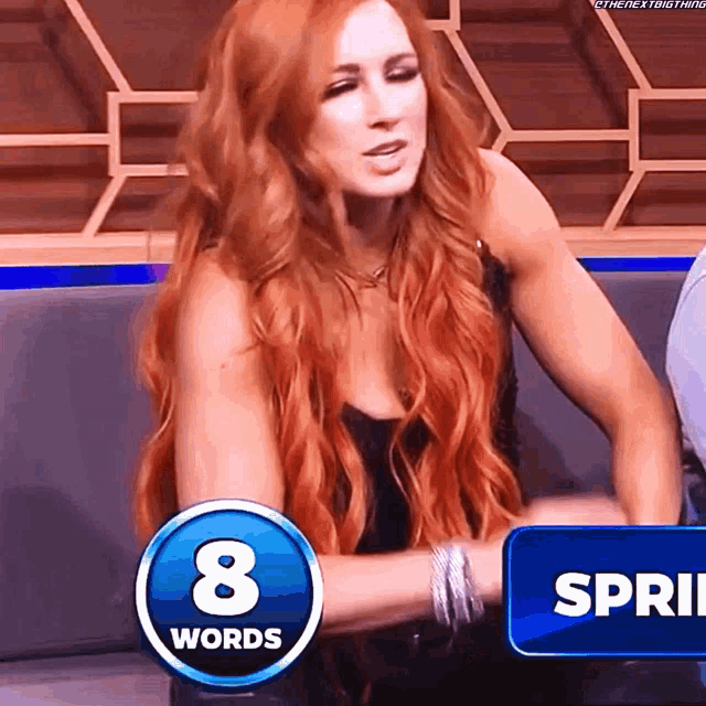 a woman with long red hair is sitting in front of a blue button that says 8 words
