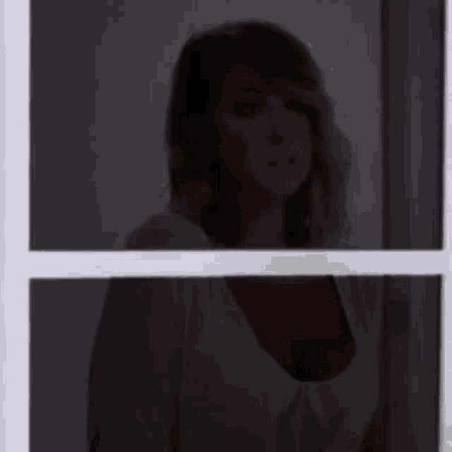 a woman is standing in front of a window looking out .