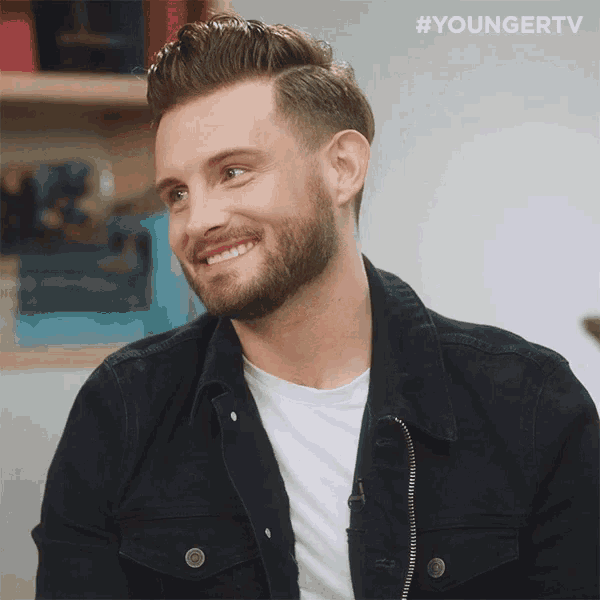 a man with a beard wearing a black jacket and a white shirt with #youngertv written on the bottom