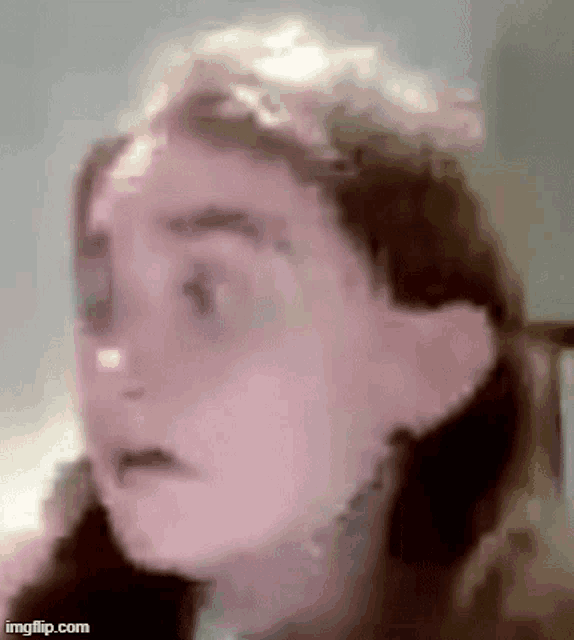 a close up of a woman 's face with a blurred background and a surprised look on her face .