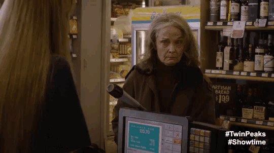 a woman behind a cash register in a store with a sign that says artisan bread