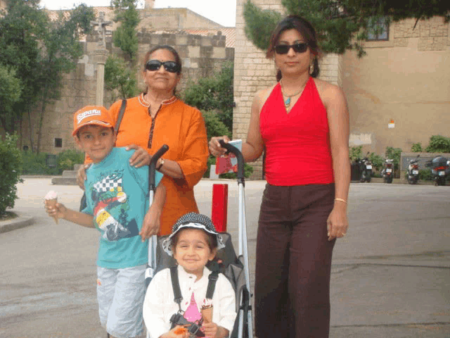 a woman in a red top is standing next to a boy wearing a shirt that says ' ferrari ' on it