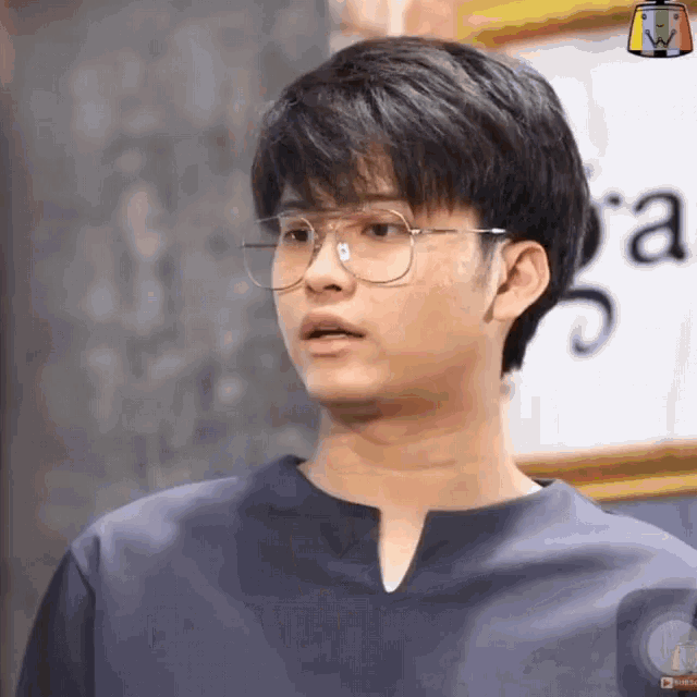 a young man wearing glasses stands in front of a sign that says " a "