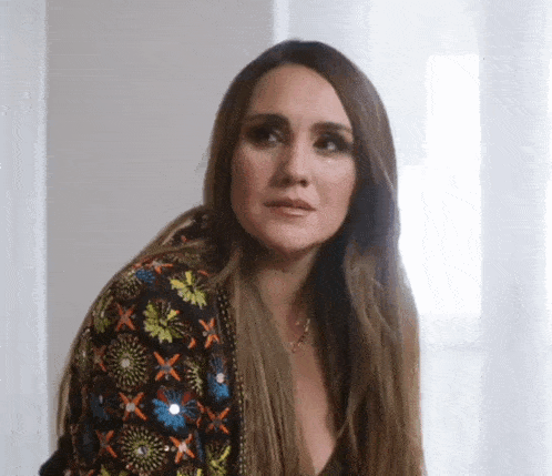 a woman with long hair is wearing a floral jacket and a necklace .