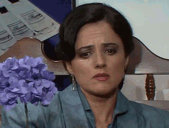 a woman sitting in a chair with purple flowers in front of her