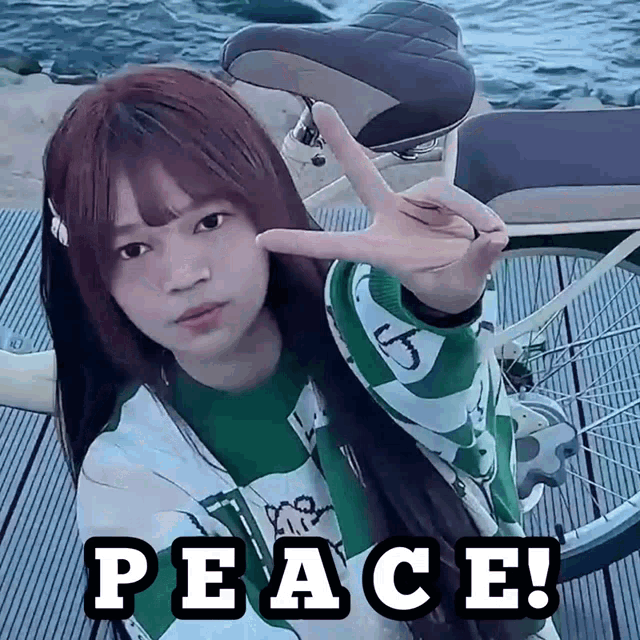 a girl in a green shirt is giving a peace sign
