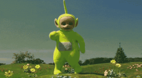 a yellow teletubbies character stands in a field of flowers