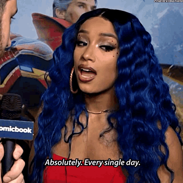 a woman with blue hair is talking into a microphone that says comicbook