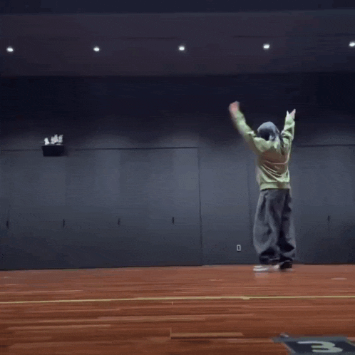 a man is doing a handstand on a wooden floor in a gym .