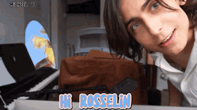 a young man says hi rosselin in front of a piano and microphone