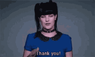 a woman in a blue shirt is making a thank you gesture .