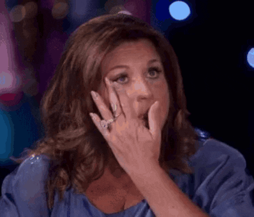 a woman with a ring on her finger is covering her mouth with her hands .