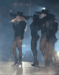 a woman singing into a microphone while standing next to two other women