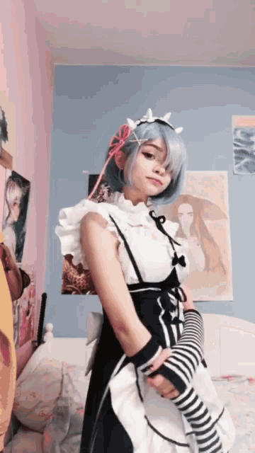 a girl in a maid costume stands in front of a bed